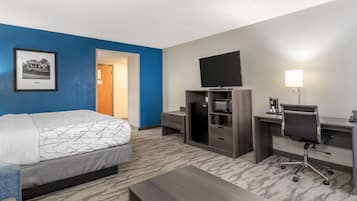 Habitación de hotel con cama, escritorio y televisión.