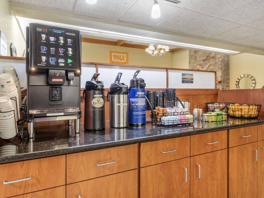 Estación de café con máquina de café, dispensadores de agua caliente y una variedad de cápsulas de café.