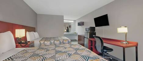 A hotel room with two beds, a desk, a chair, a TV, and a lamp.