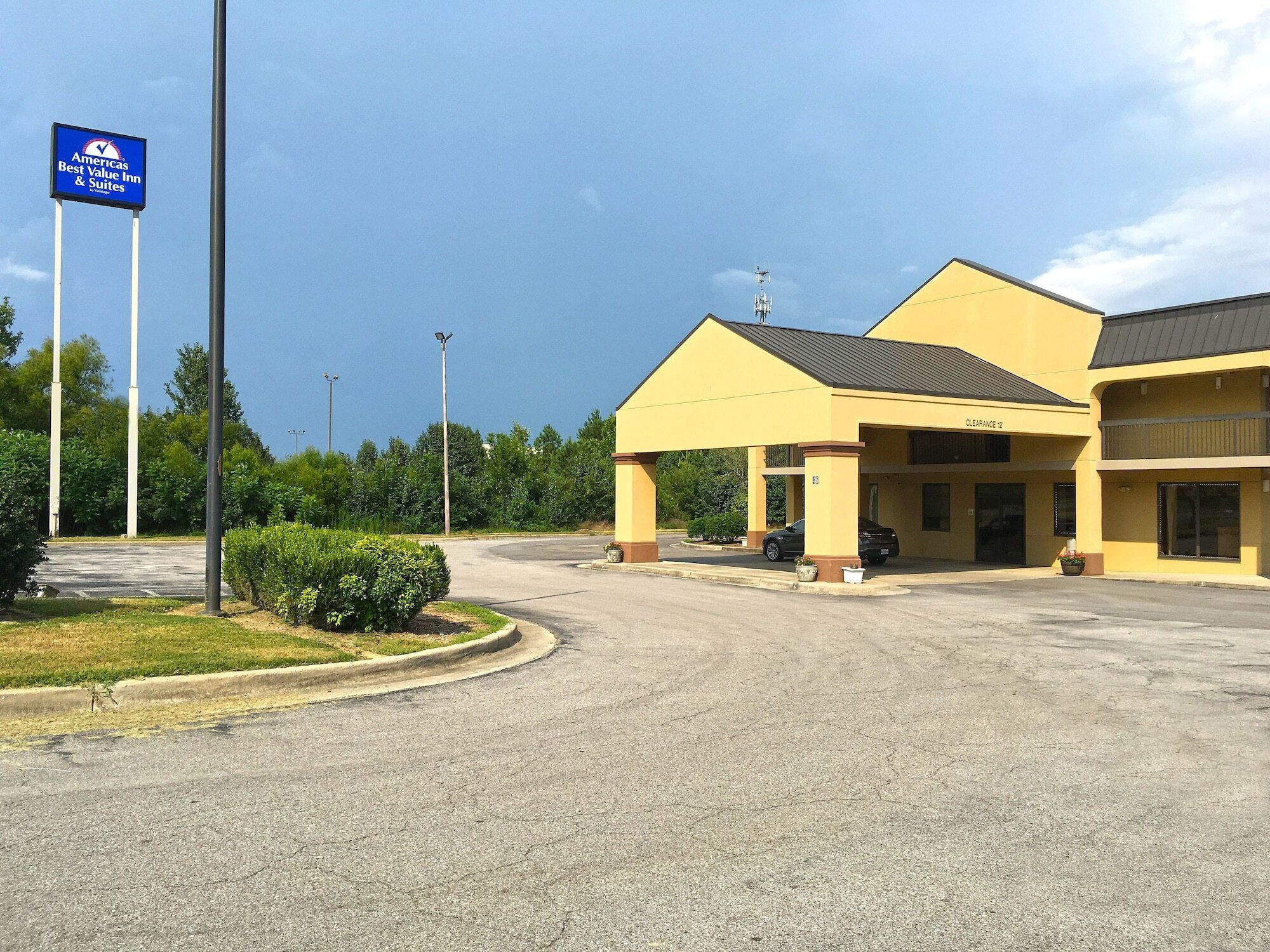 A Best Value Inn & Suites with a clear sky, a parking lot, and a building with a yellow facade.