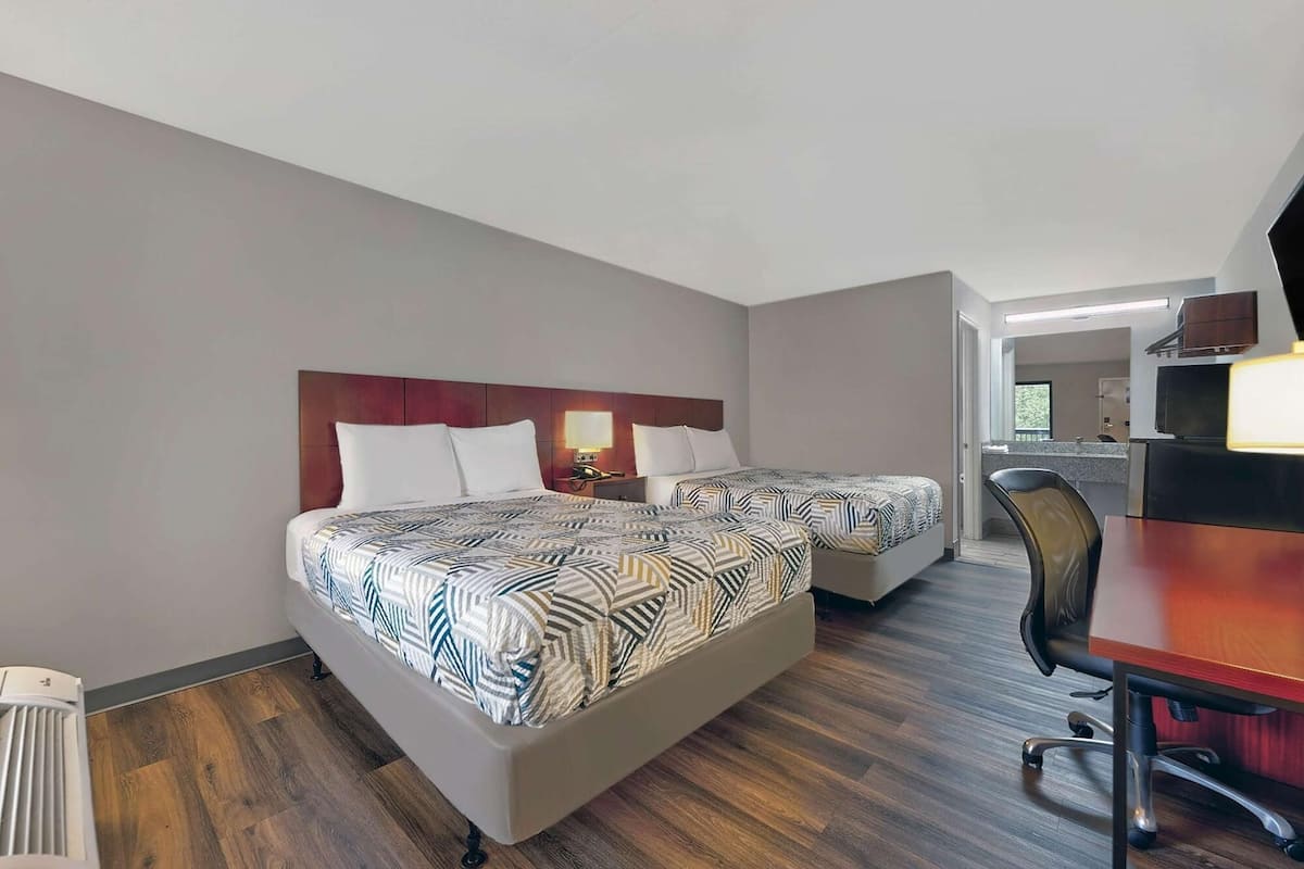 Ein Hotelzimmer mit zwei Betten, einem Schreibtisch und einer Küchenzeile.