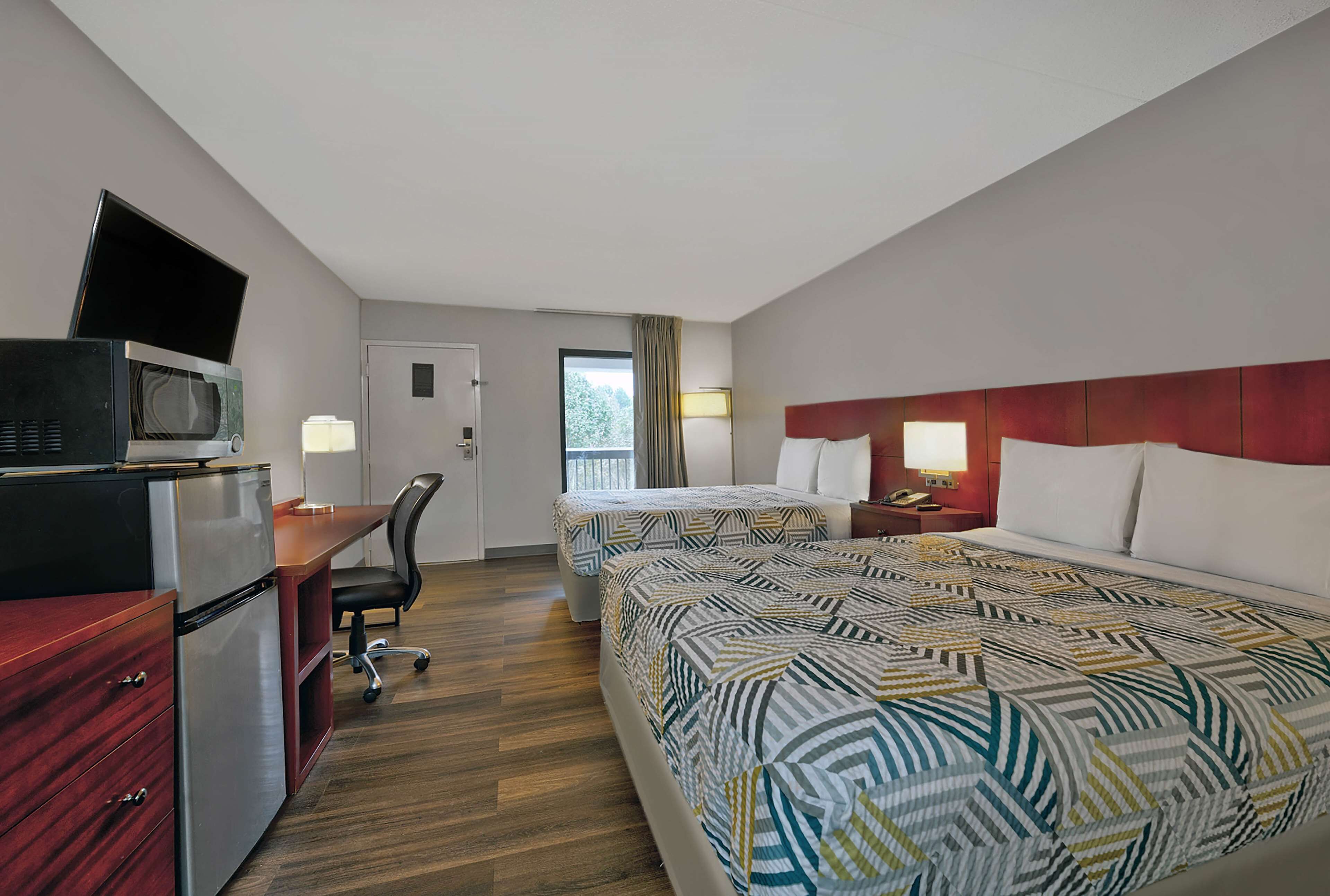 Une chambre d’hôtel avec deux lits, un bureau équipé d’un ordinateur et d’un micro-ondes, ainsi qu’une petite télévision.