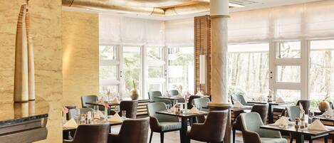 A restaurant with multiple tables and chairs, large windows, and a modern interior design.