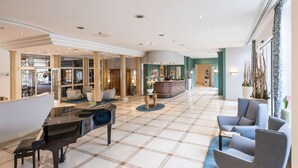 A spacious lobby with a grand piano, seating area, and a reception desk. - Dorint Venusberg Bonn (Bonn)