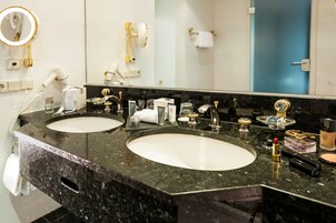Un baño con dos lavamanos, un espejo grande y distintos artículos de aseo.