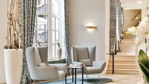 A modern living room with two grey armchairs, a small table, and a large window with patterned curtains. - Dorint Venusberg Bonn (Bonn)