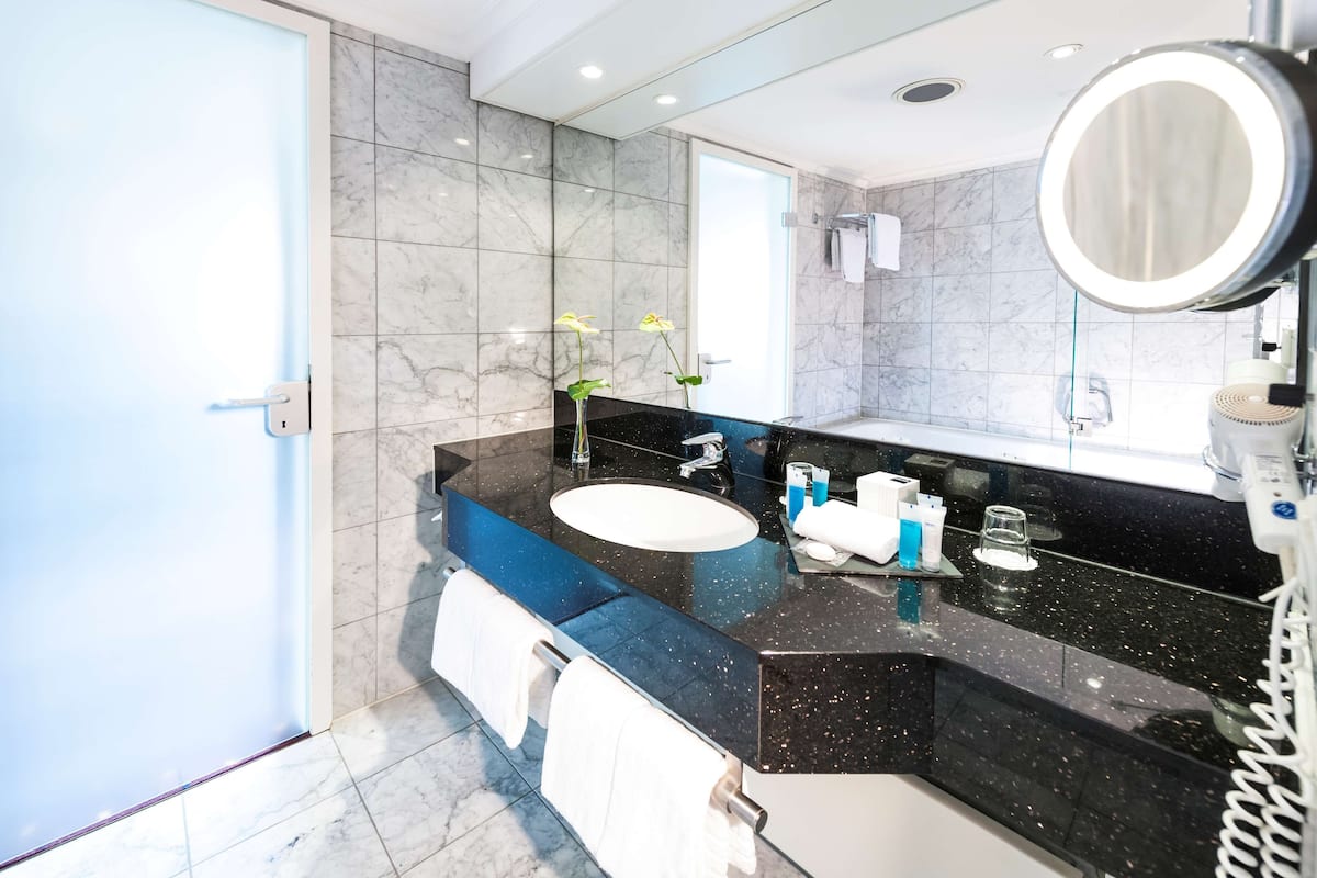 A modern bathroom with a black marble countertop, a white sink, and a large mirror.