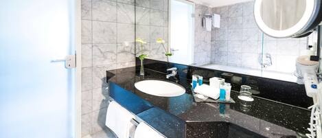 A modern bathroom with a black marble countertop, a white sink, and a large mirror.