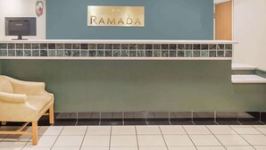 A reception desk with a sign that reads "RAMADA," a television, and a seating area. - Ramada by Wyndham Columbia (Columbia)