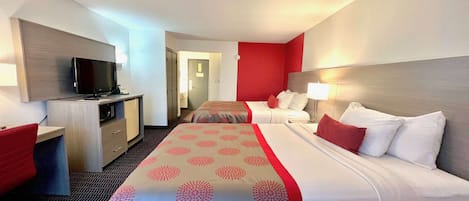 A hotel room with a bed, a desk, a television, and a door leading to another room.