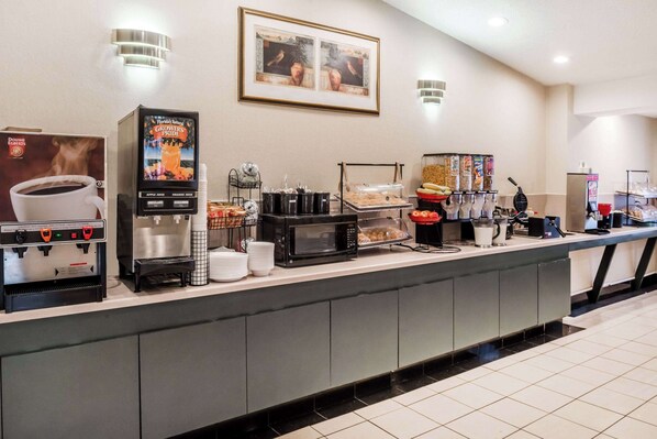 A self-service breakfast bar with coffee machines, a microwave, and various food options. - Ramada by Wyndham Columbia (Columbia)