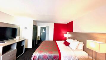 Een hotelkamer met een bed, televisie, bureau en lamp.