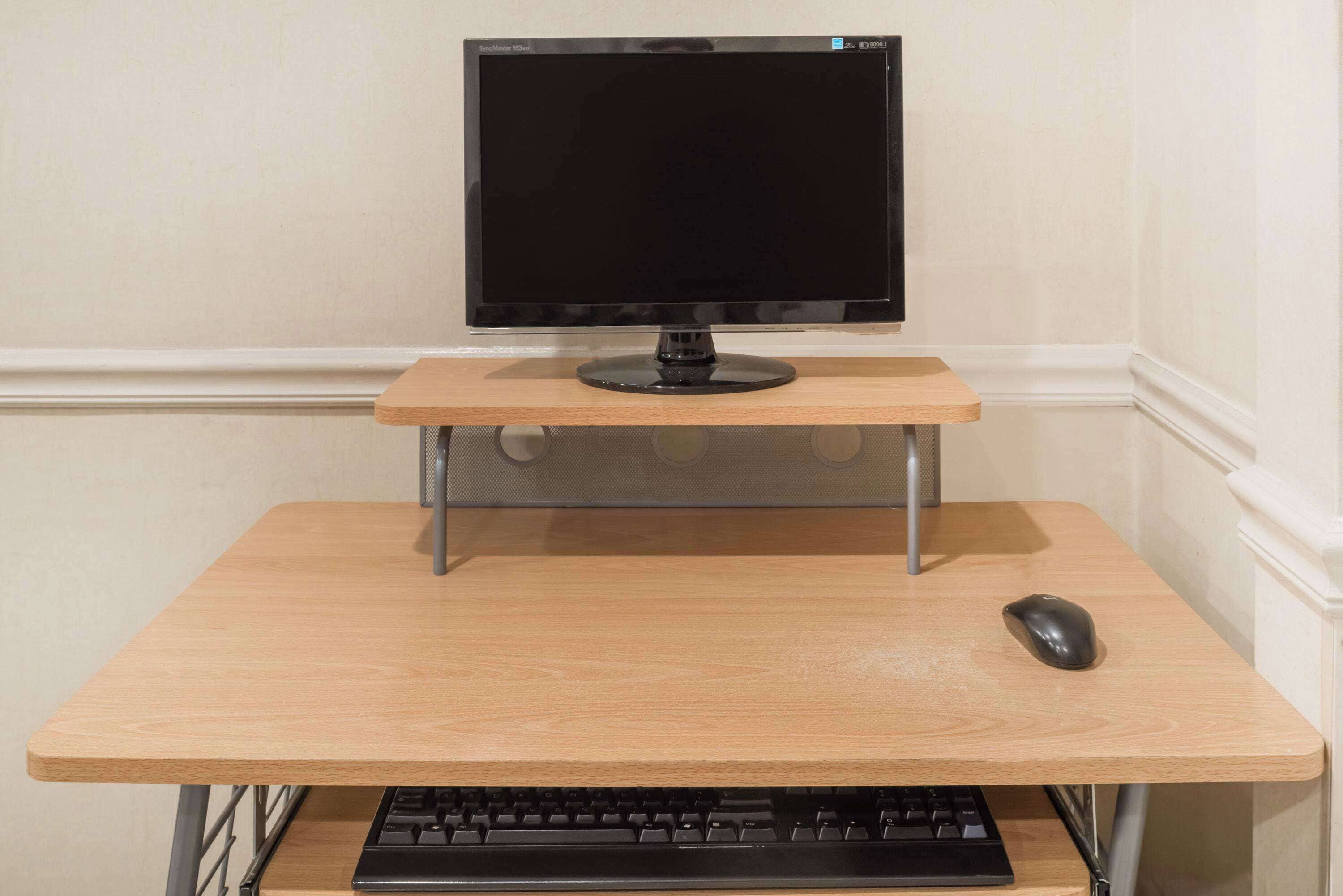 A computer desk with a monitor, keyboard, and mouse.