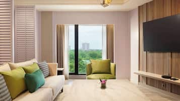 Una sala de estar moderna con un sofá, un sillón verde, una mesa de centro y un televisor montado en la pared.