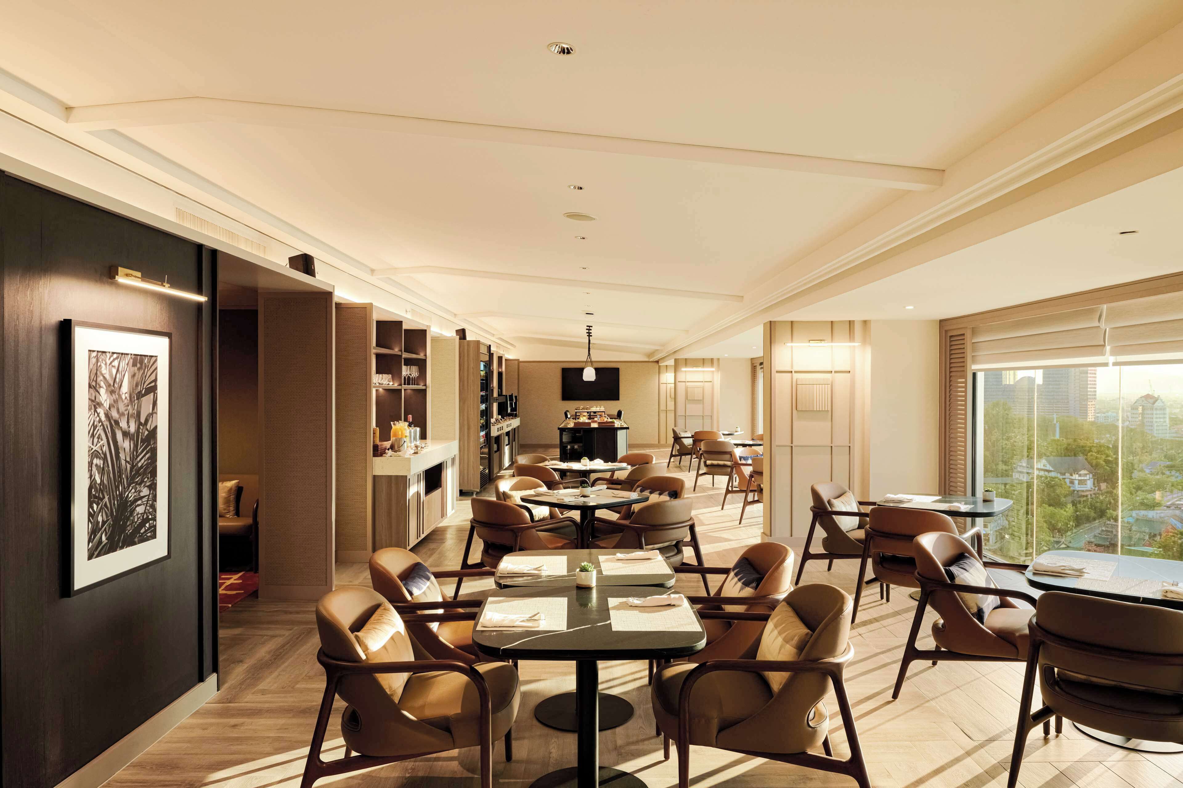 Un comedor amplio con varias mesas y sillas, un ventanal con vistas a la ciudad y una decoración de estilo moderno.