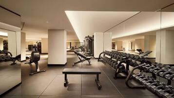 A modern gym with various exercise equipment, including dumbbells, benches, and weight machines.