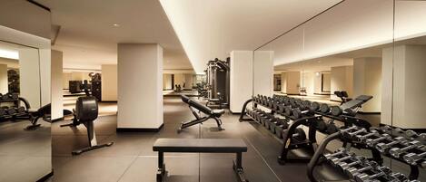 Un gimnasio moderno con diverso equipamiento de ejercicio, incluyendo mancuernas, bancos y máquinas de pesas.
