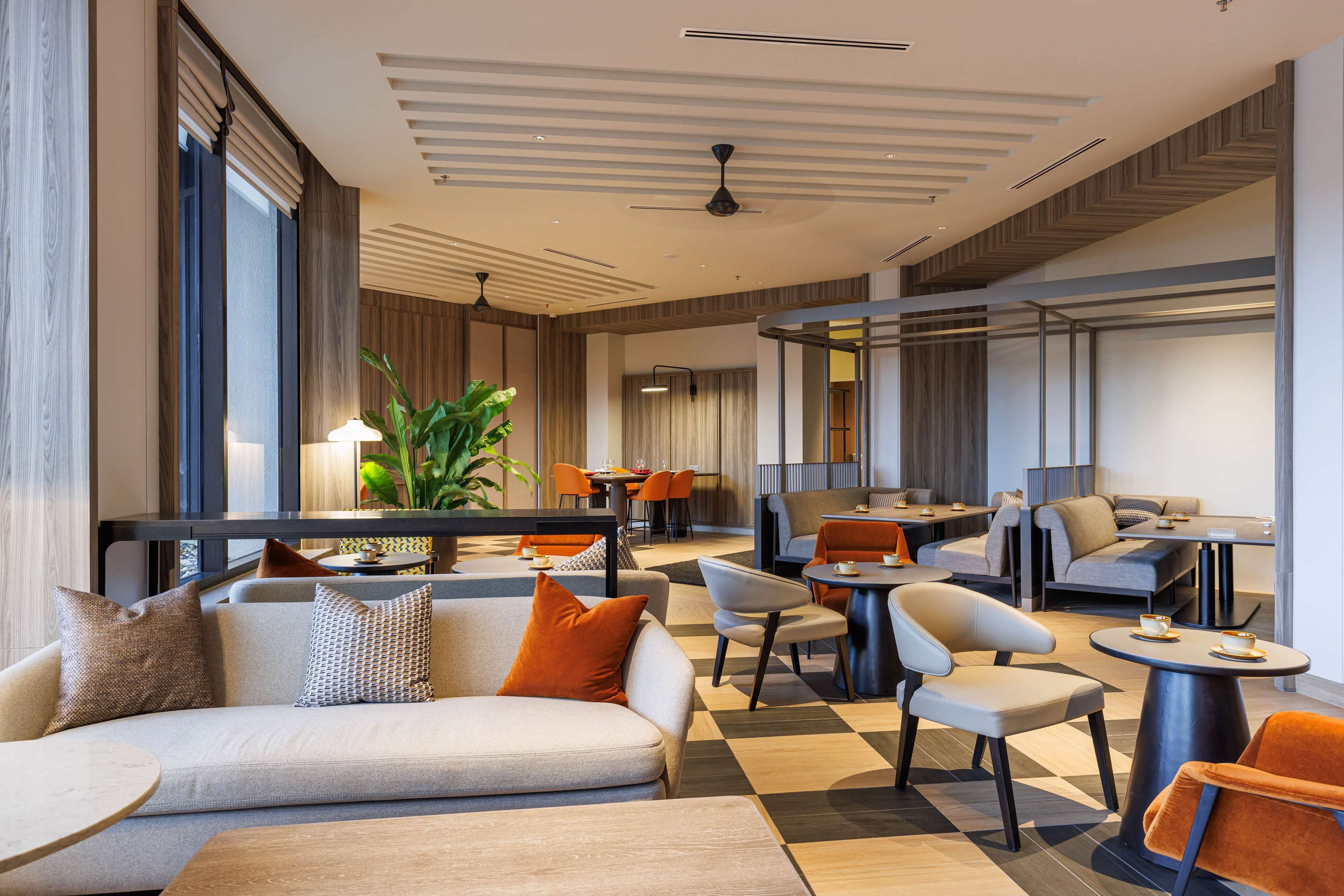 A modern hotel lobby with a checkered floor, sofas, chairs, and tables.