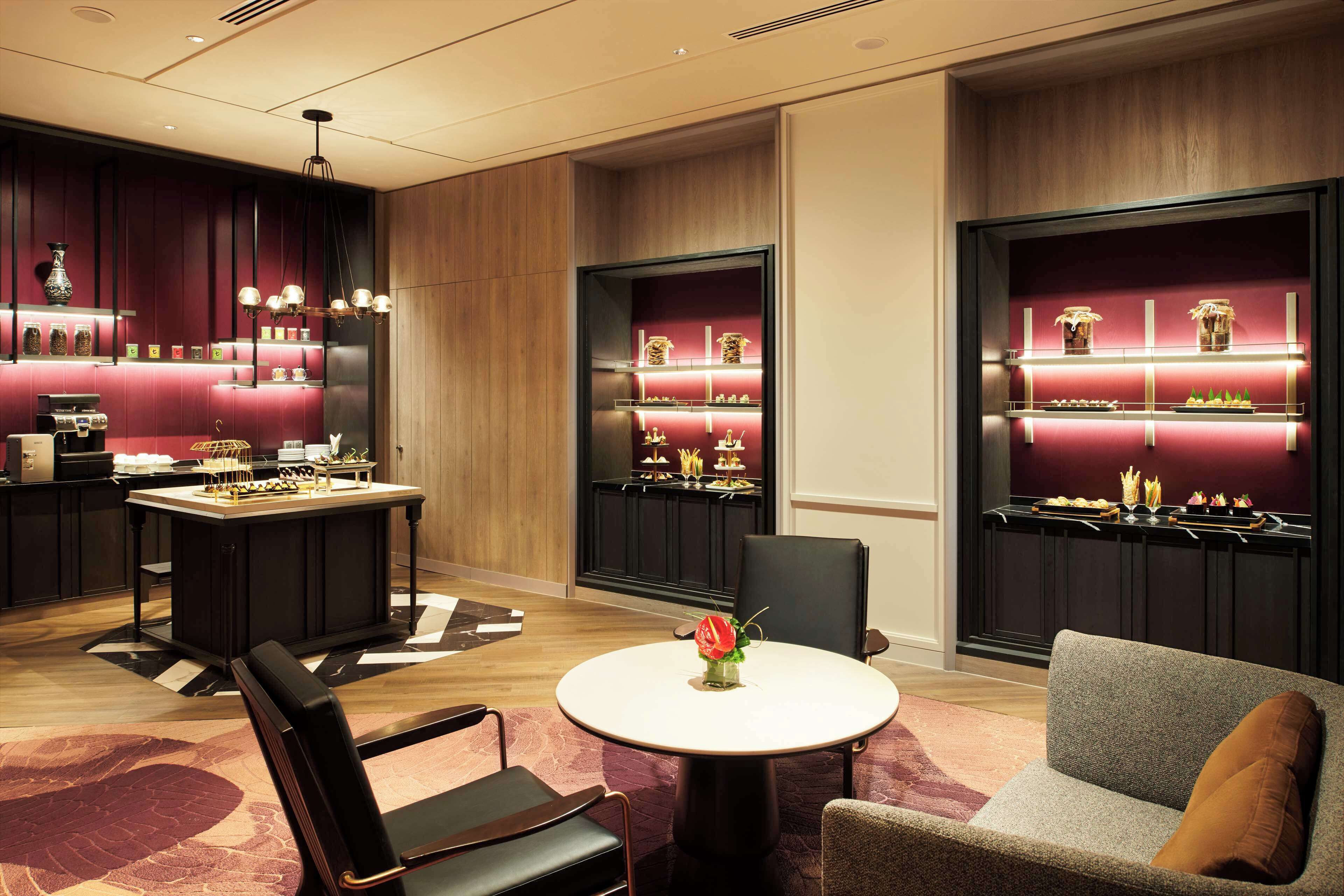 Um hall de hotel moderno com área de bar, assentos e peça central decorativa.