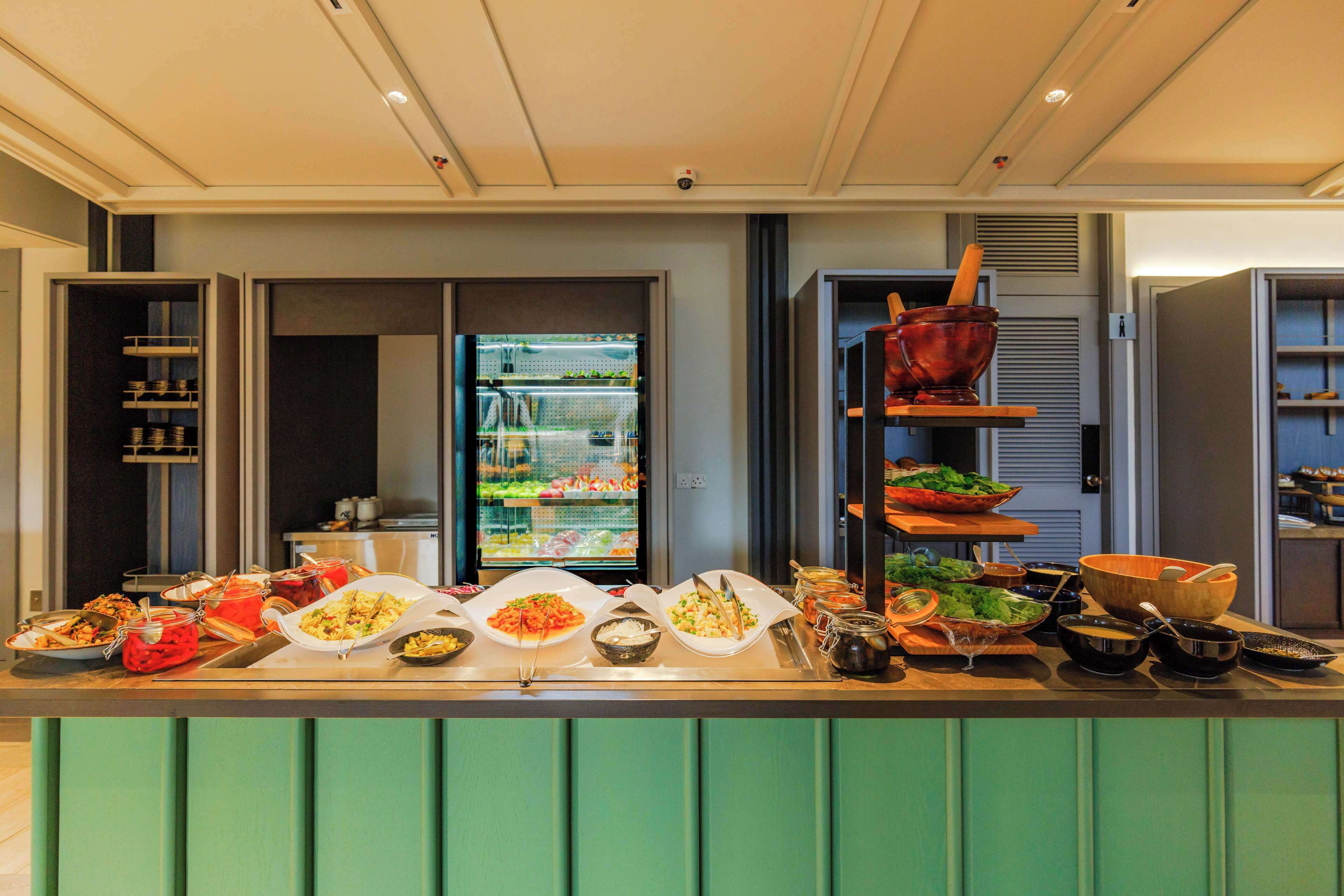 Balcão de buffet com diversos alimentos e utensílios.