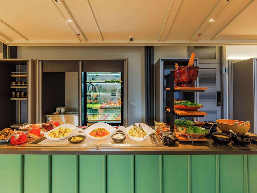 Balcão de buffet com diversos alimentos e utensílios.
