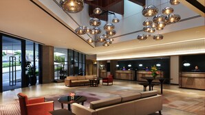 A spacious lobby with a large sofa, red chairs, and a dining area. - Hilton Kuching (Kuching)