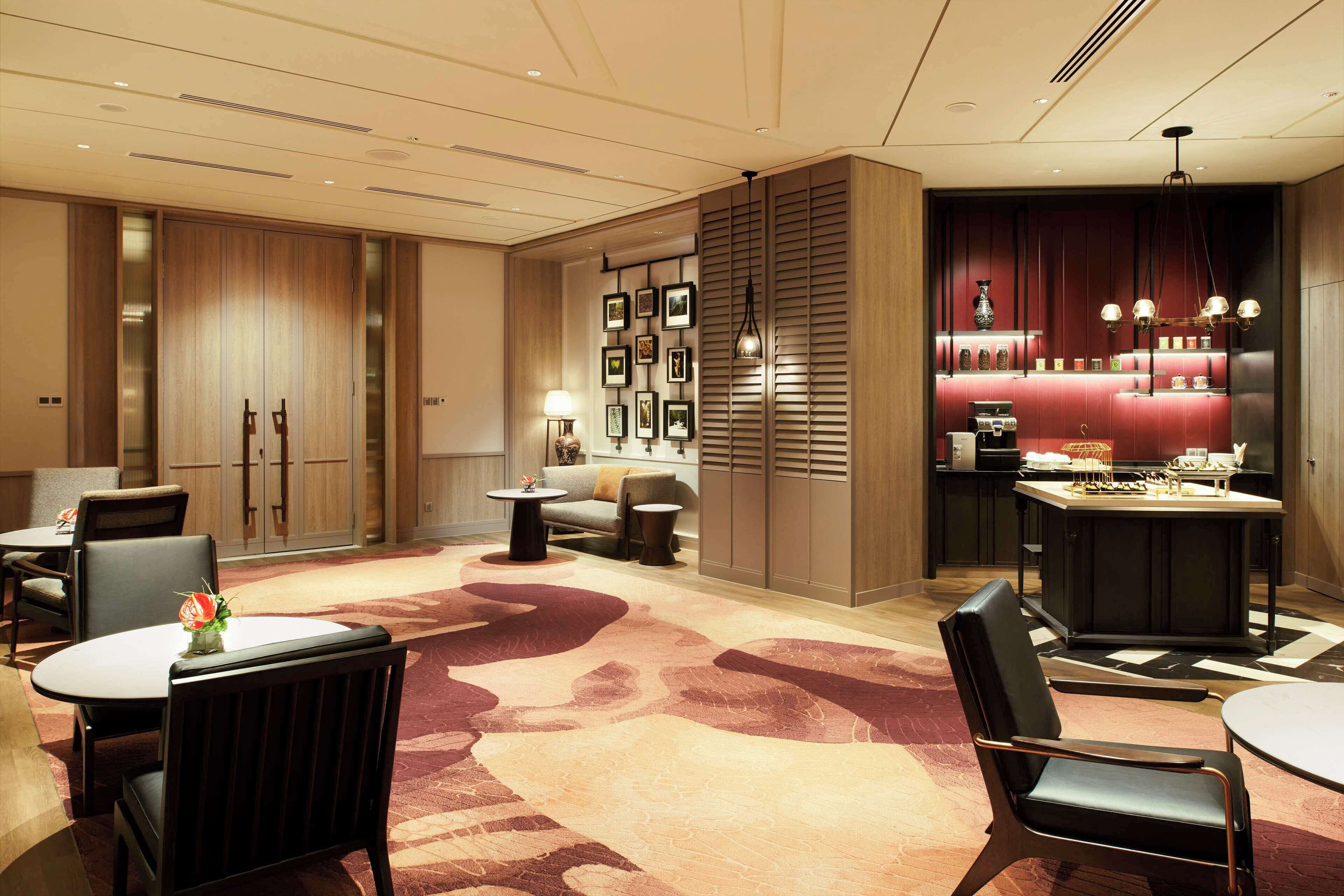 A hotel lobby with a reception desk, seating area, and a bar.