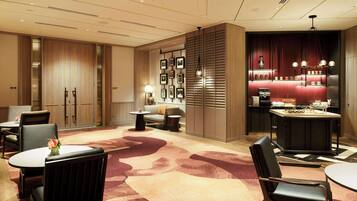 A hotel lobby with a reception desk, seating area, and a bar.