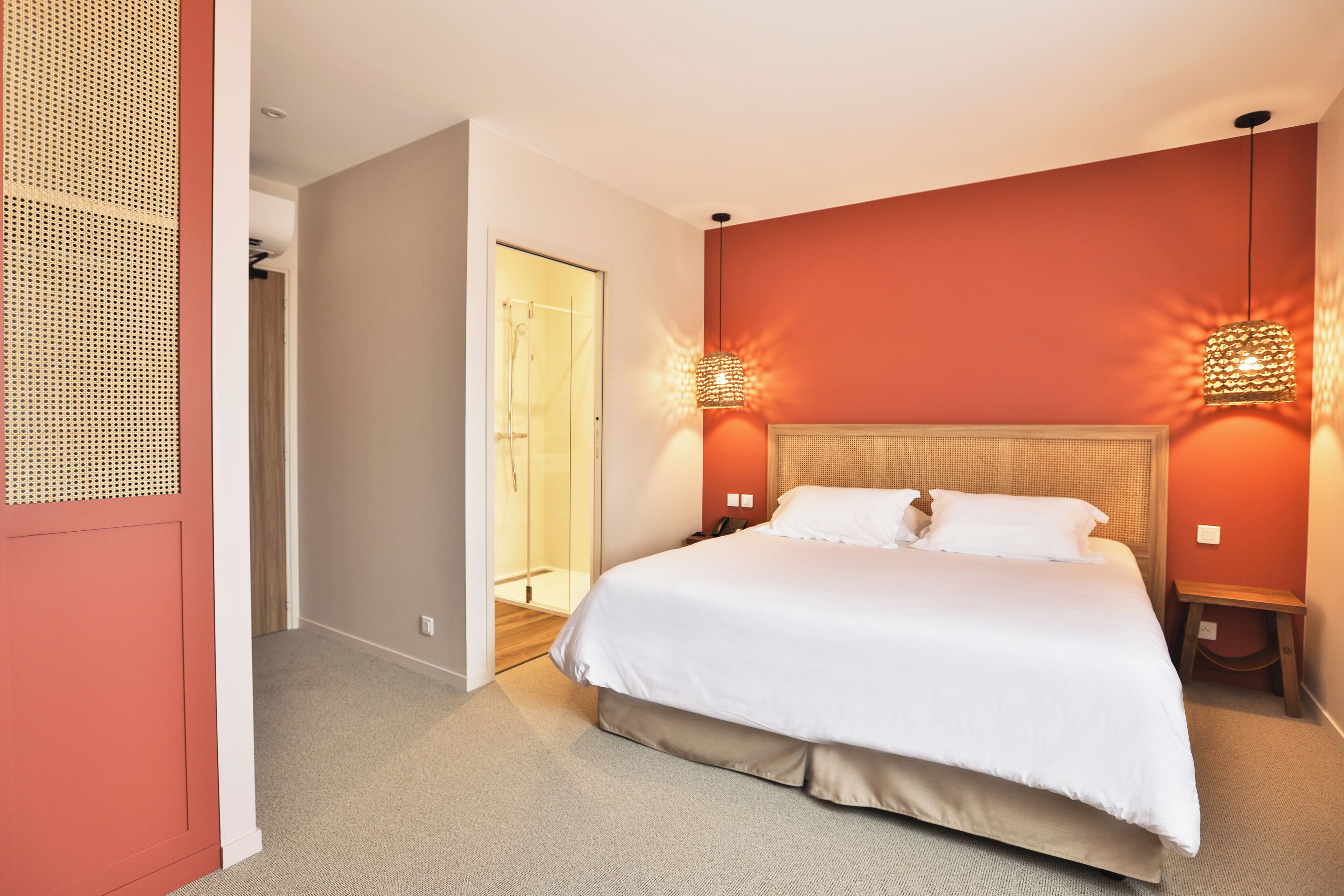 A hotel room with a large bed, two bedside tables, a headboard, and two wall-mounted lamps.