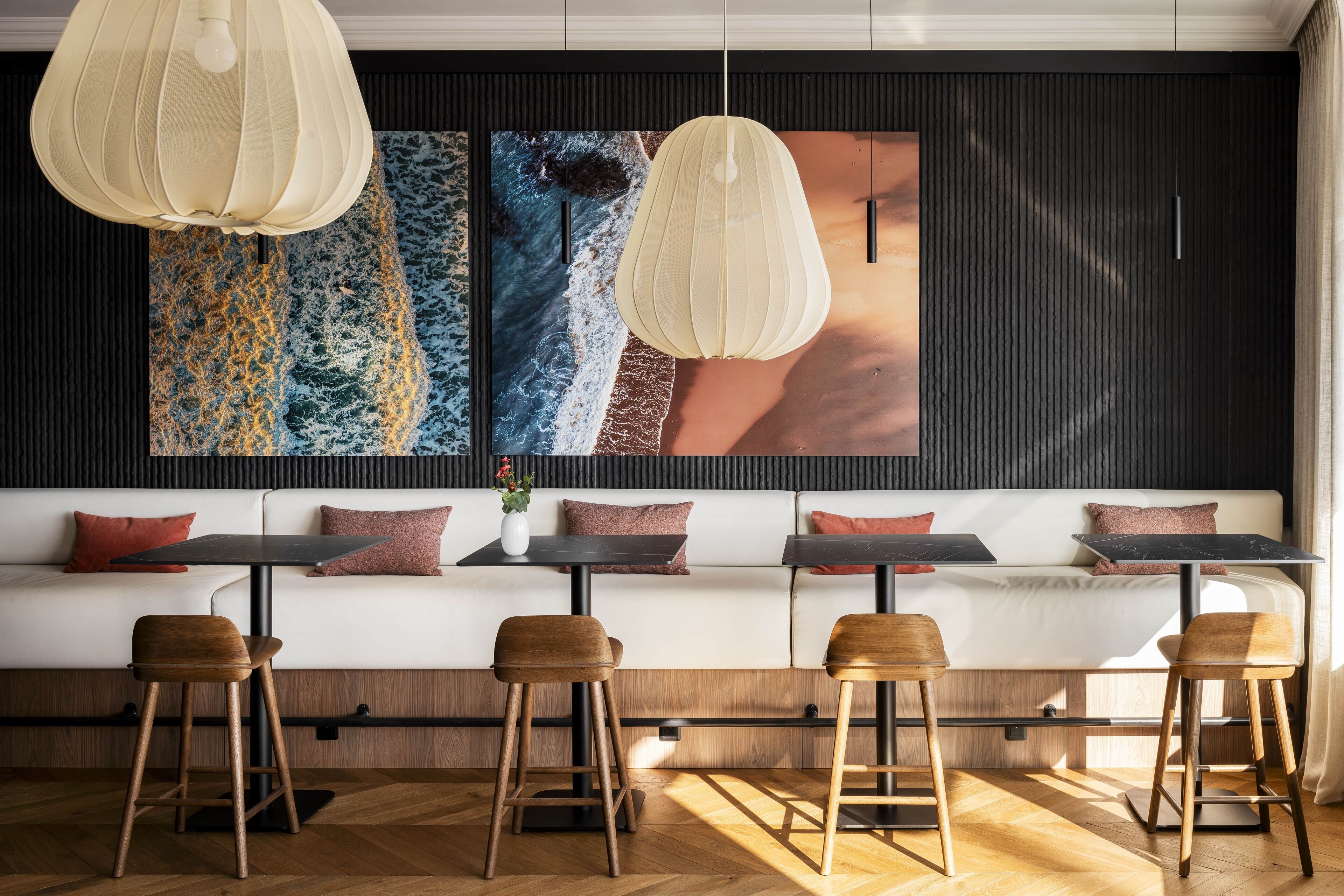 Ein modernes Interieur mit einem weißen Sofa, Holzschemeln und Pendelleuchten.
