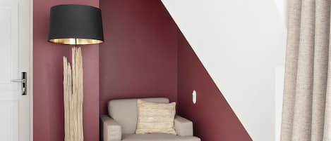 Una sala de estar moderna con techo alto, un sofá, una lámpara de pie y una alfombra estampada.