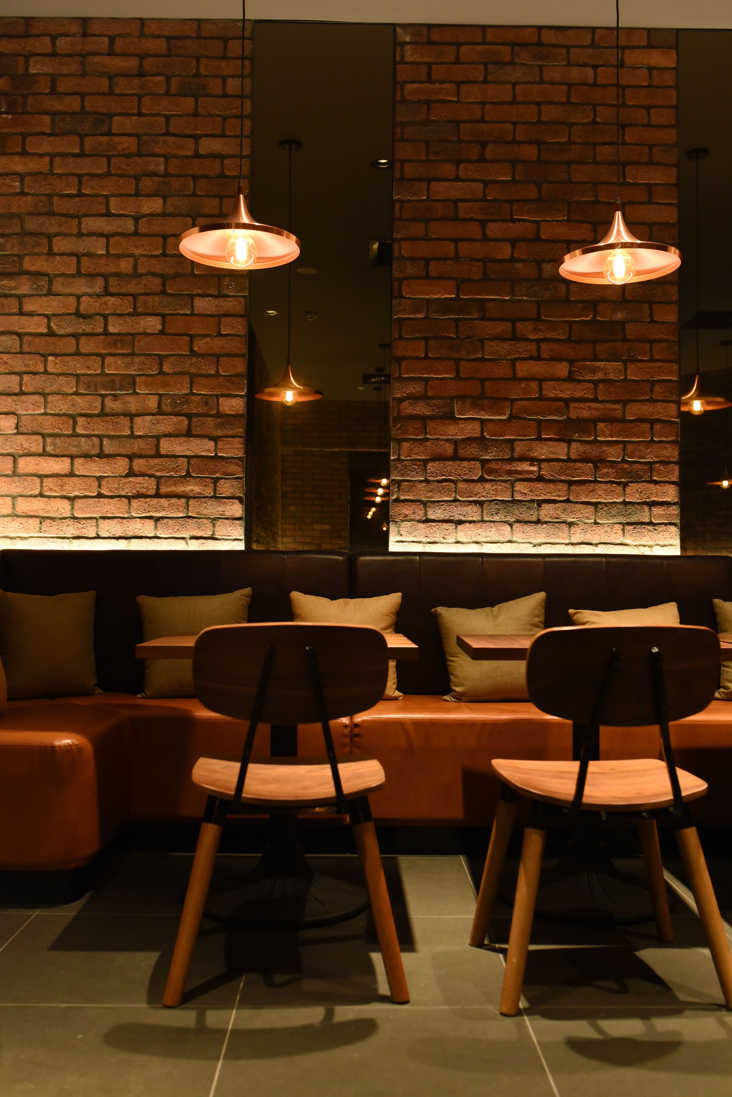 Un interior moderno con pared de ladrillo, un sofá de madera y dos sillas de madera.