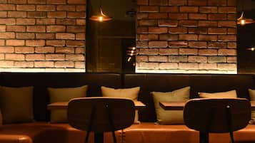 A modern interior with a brick wall, a wooden sofa, and two wooden chairs.