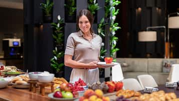 Una mesa de buffet con diversos alimentos y una persona sosteniendo un plato con un postre.