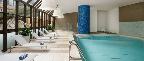 Un espace piscine doté de chaises longues et d’une balustrade en verre.