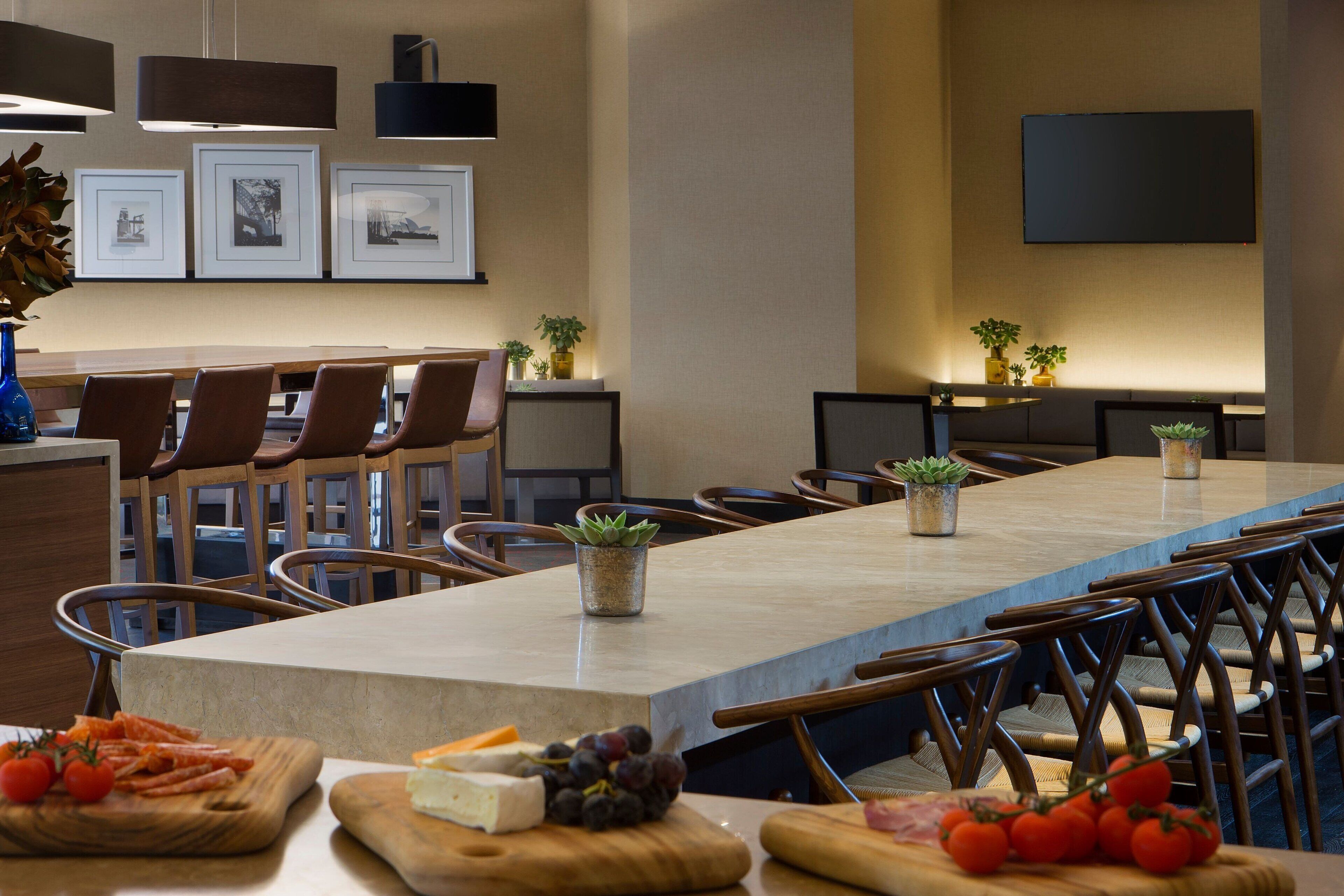 A spacious dining area with a long table, multiple chairs, and a variety of food items on the table.
