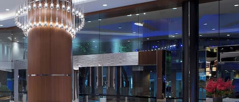 A modern lobby with a large wooden column, a circular seating area, and a glass facade.