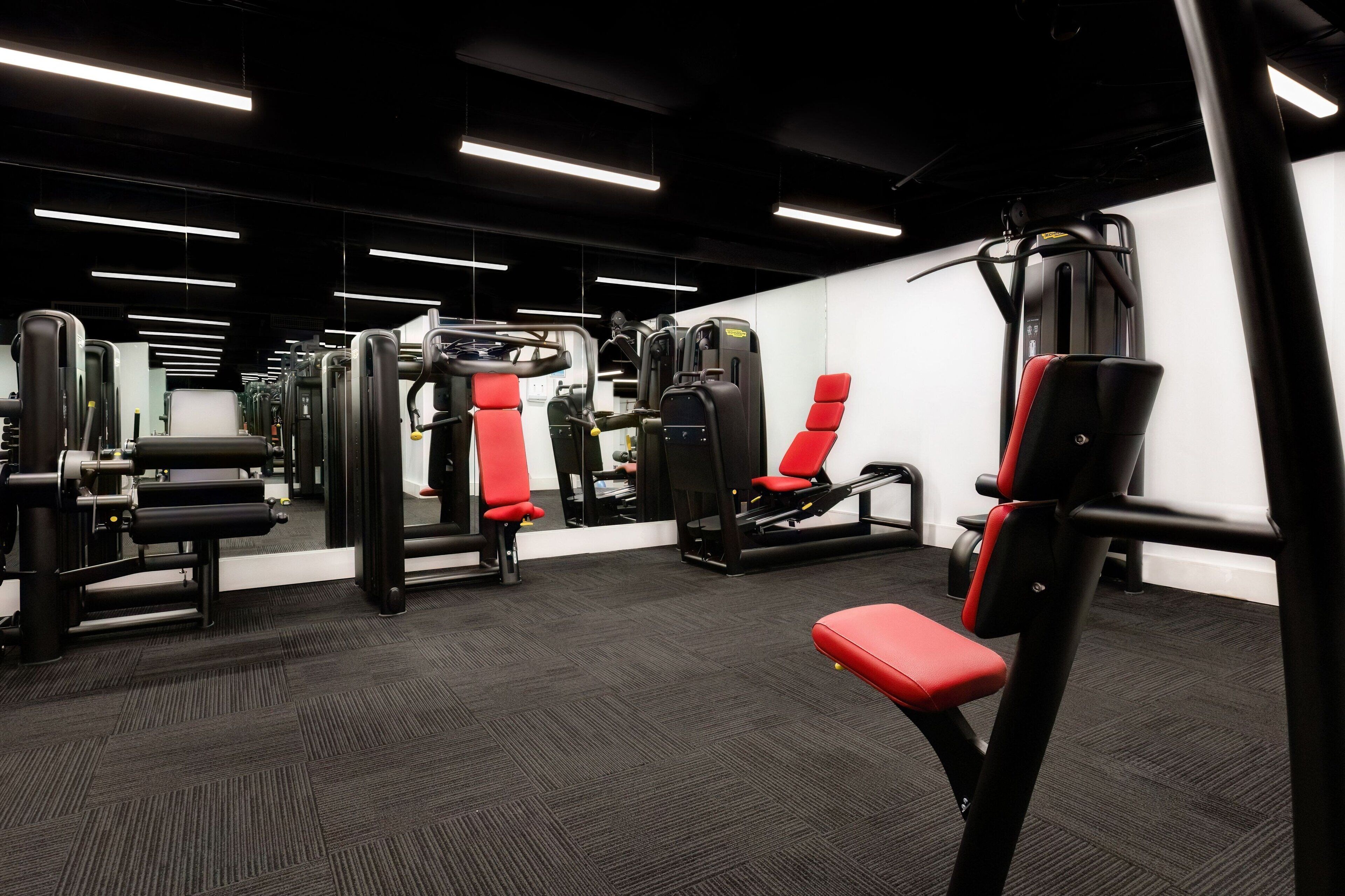 A gym with various exercise machines, including weight benches and a squat rack.