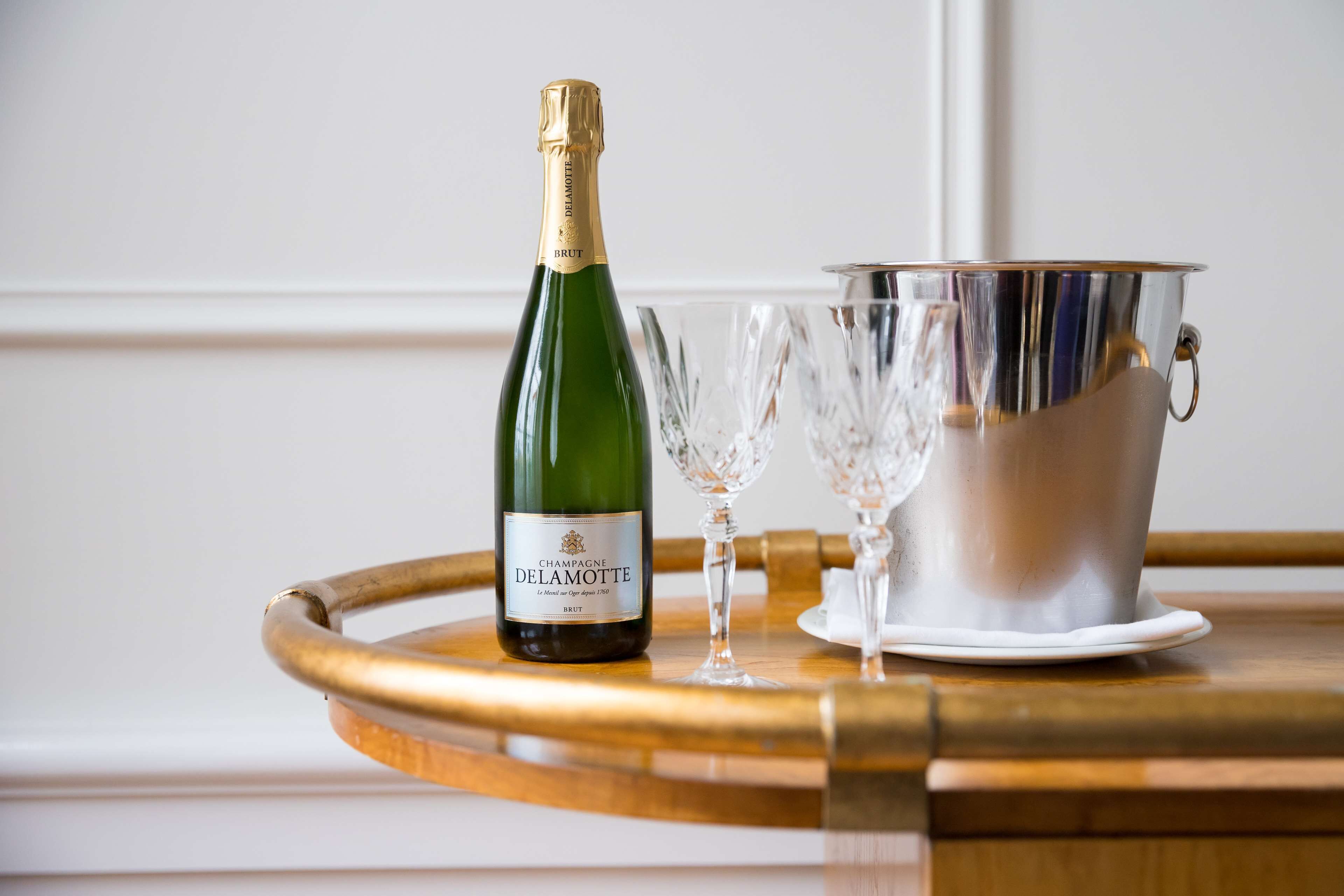 A bottle of champagne, two glasses, and a silver bucket on a wooden tray.