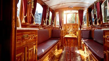 A luxurious cabin with wooden paneling, plush seating, and a ship's wheel.