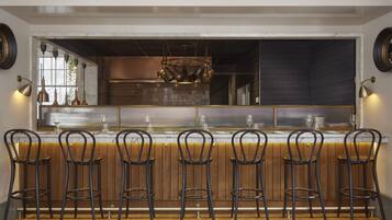 Un espace bar avec six tabourets, un comptoir en marbre et un luminaire suspendu.
