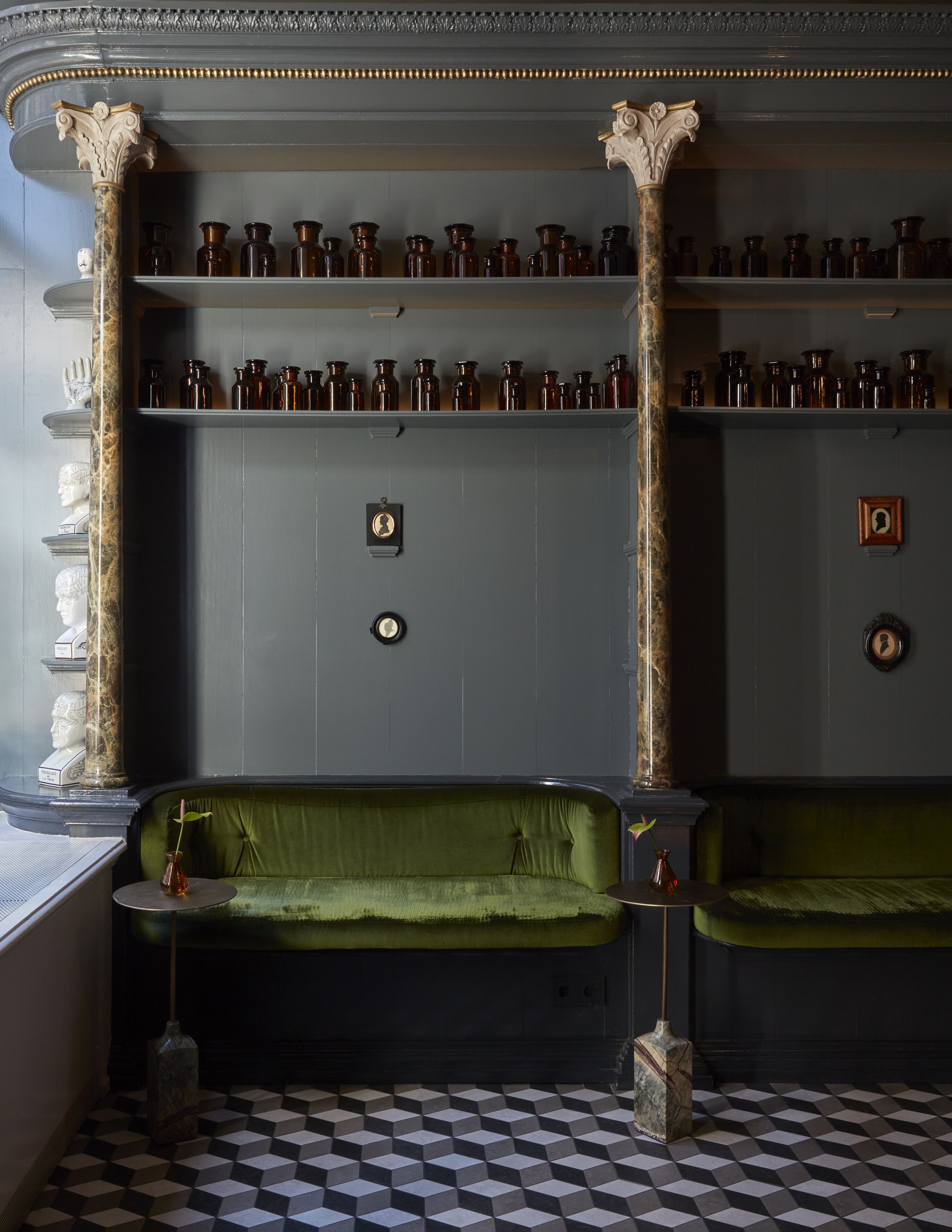 Een kamer met een geruite vloer, een groene bank en planken met flessen.