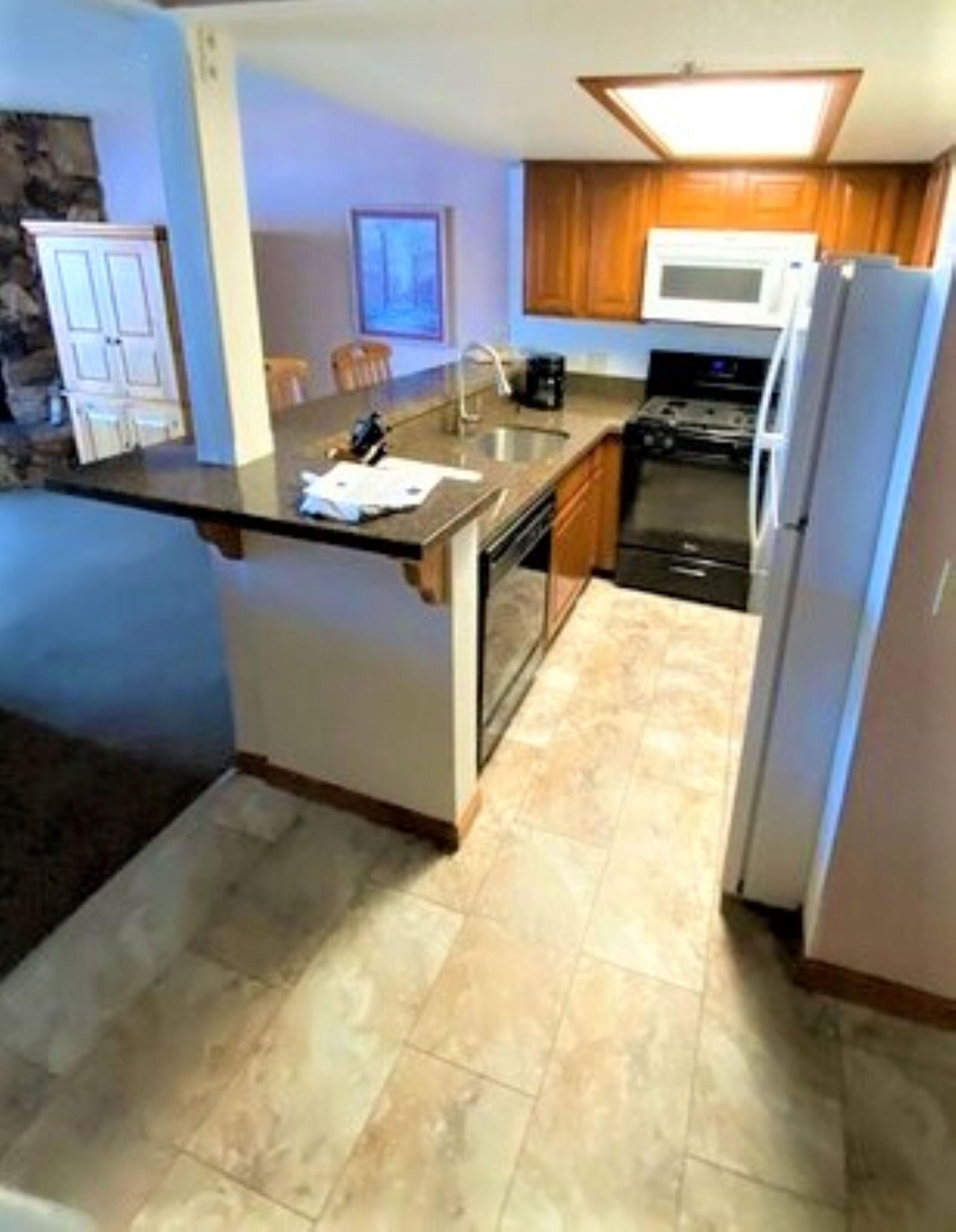 A kitchen with a central island, stainless steel appliances, and wooden cabinets.