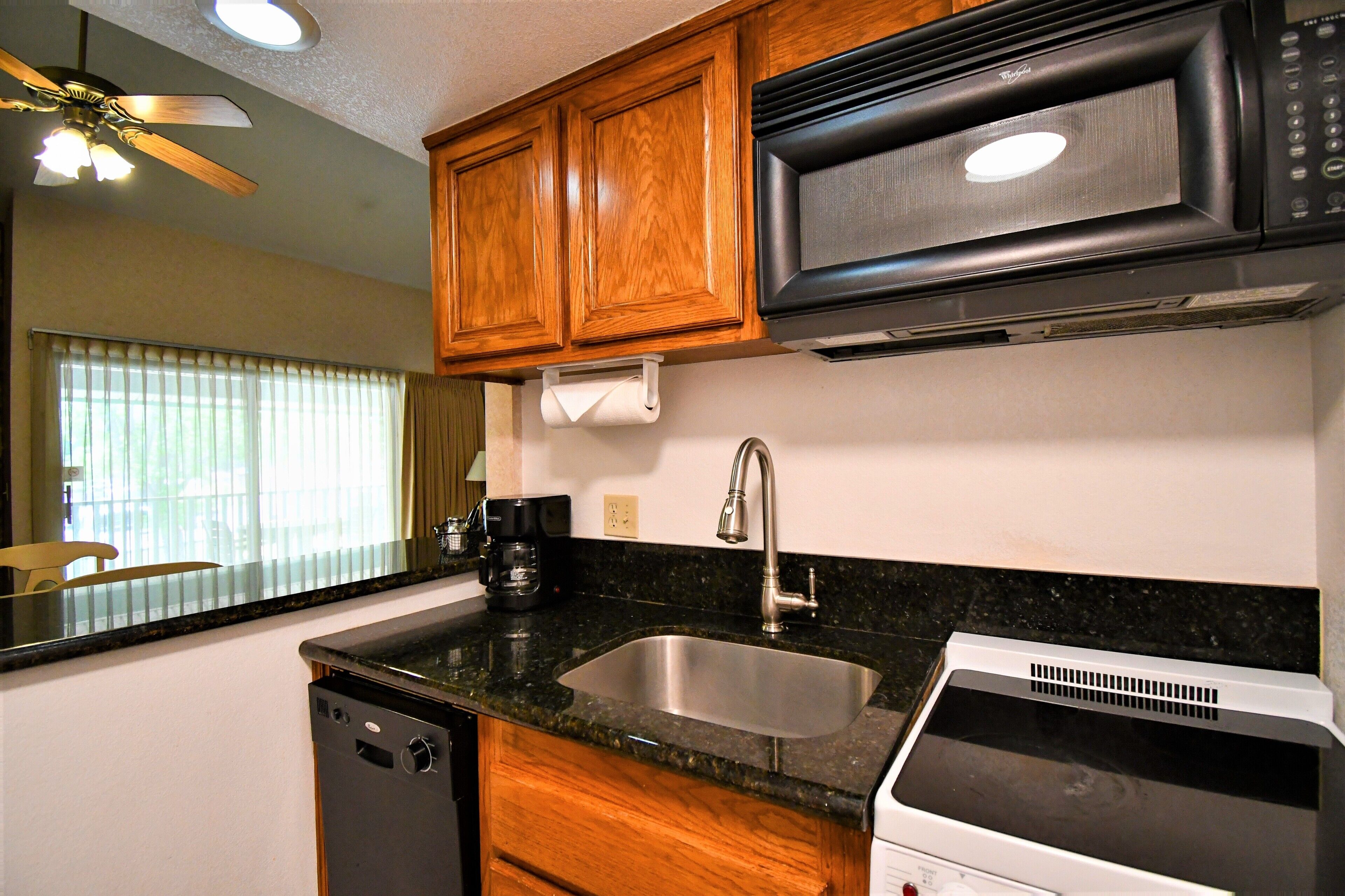 A kitchen with wooden cabinets, a stainless steel sink, a microwave, and a dishwasher.