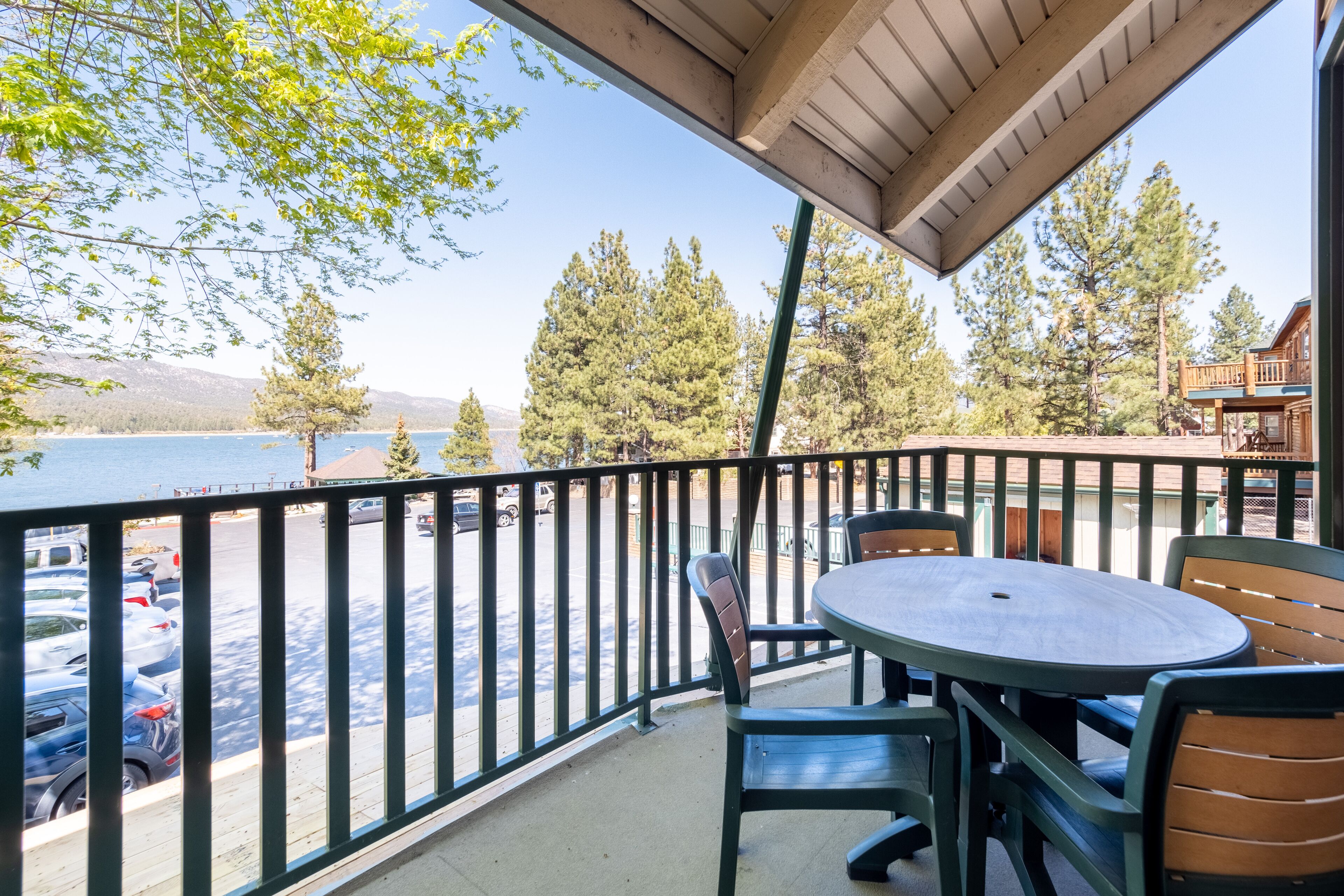 A balcony with a view of a lake and mountains, featuring a table and chairs.