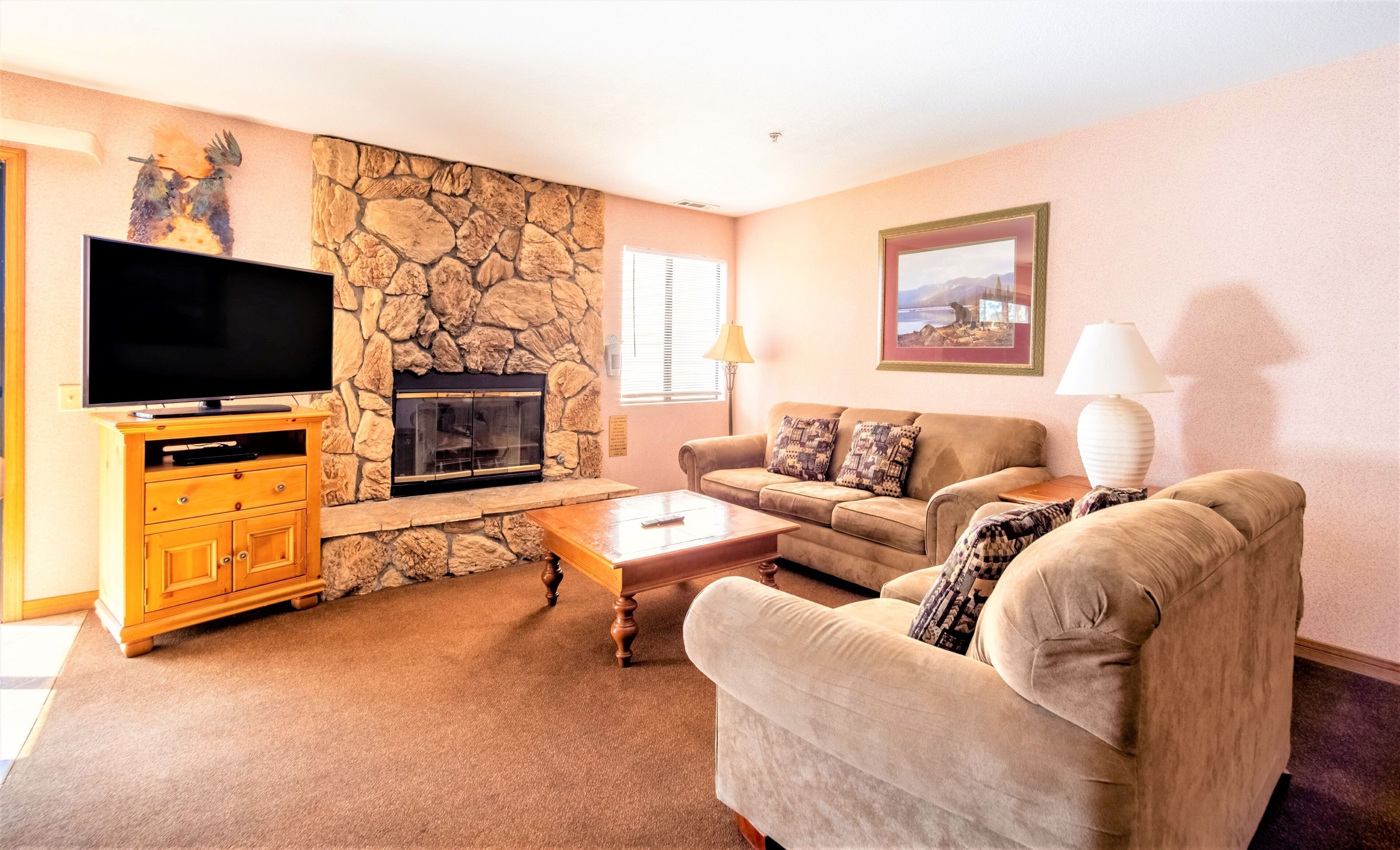 A living room with a stone wall, a fireplace, a television, a sofa, and a coffee table.
