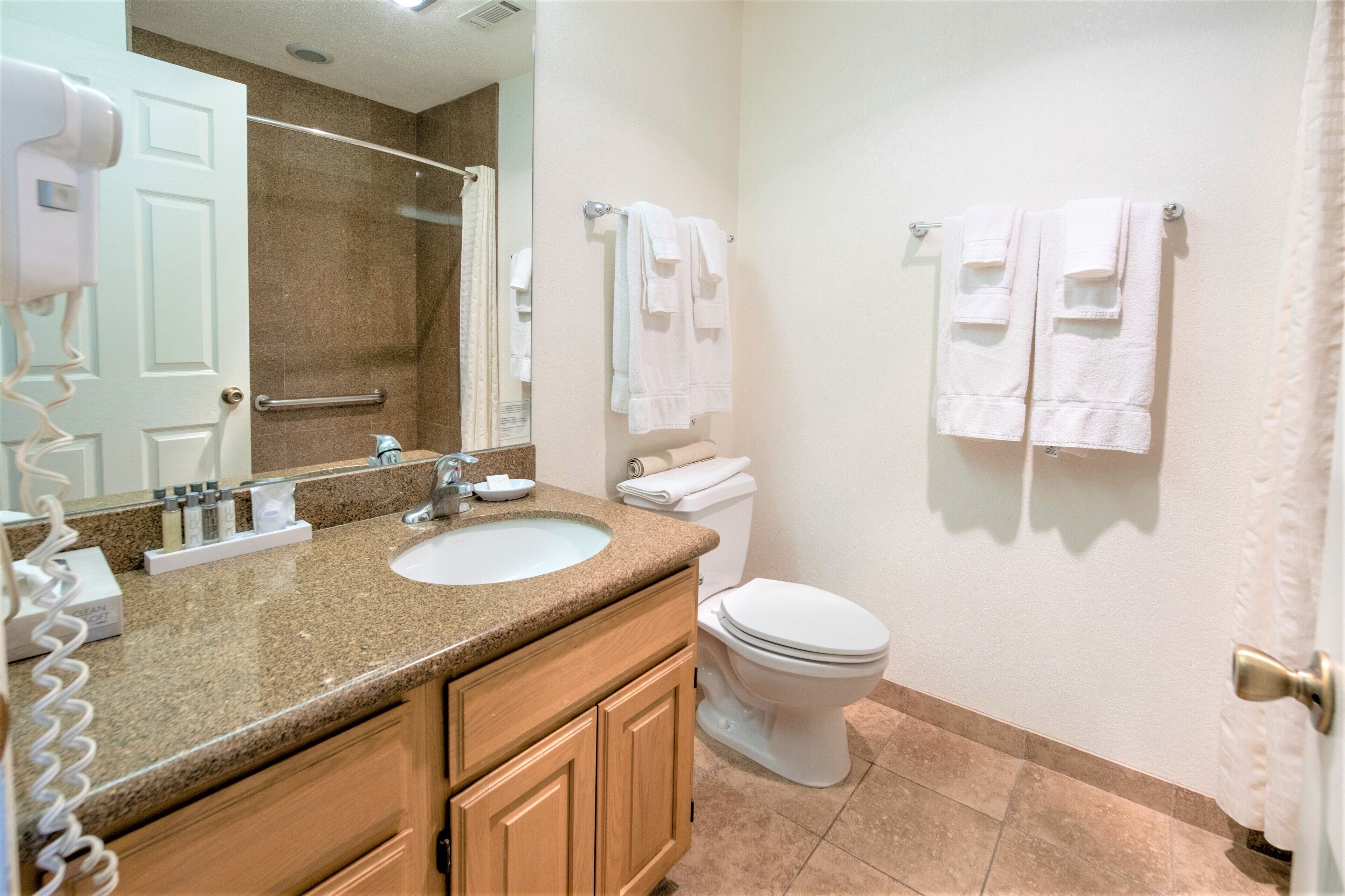 A bathroom with a granite countertop sink, a white toilet, and a towel rack.