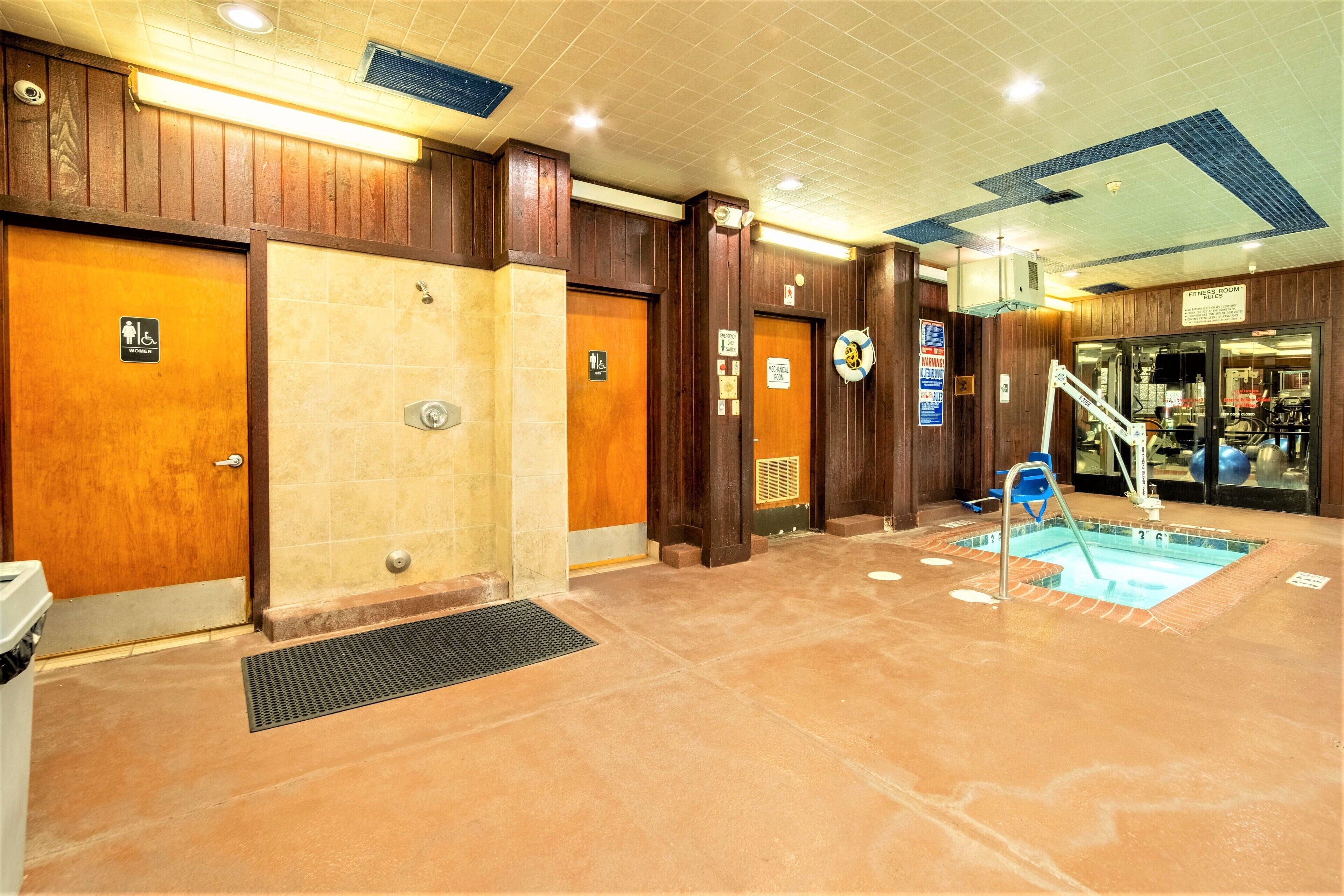 Zona de piscina con trampolín, vestuario y gimnasio.