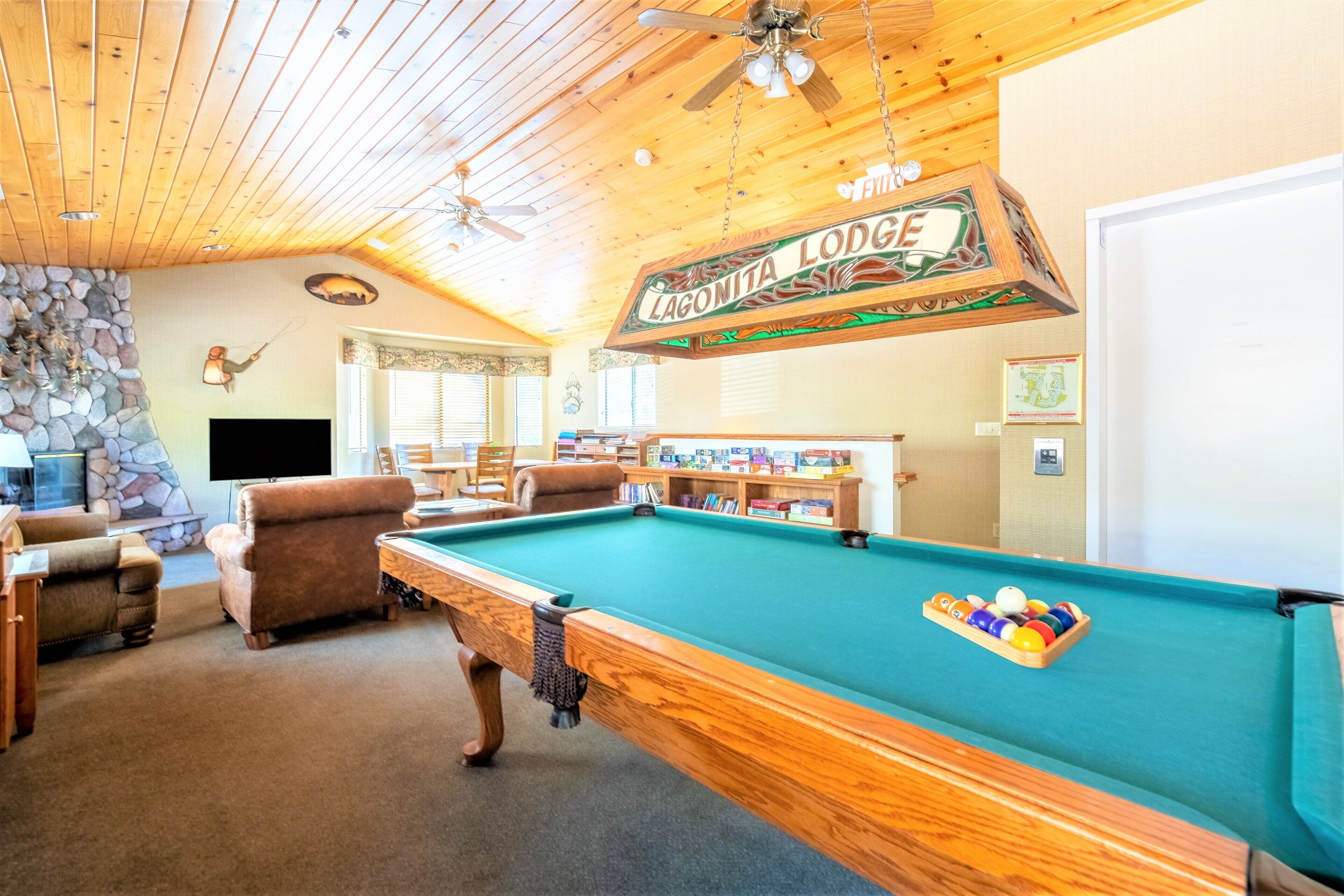 Une table de billard dans un chalet avec des plafonds en bois et des murs en pierre.