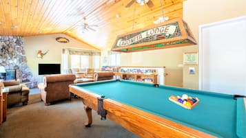 Une table de billard dans un chalet avec des plafonds en bois et des murs en pierre.